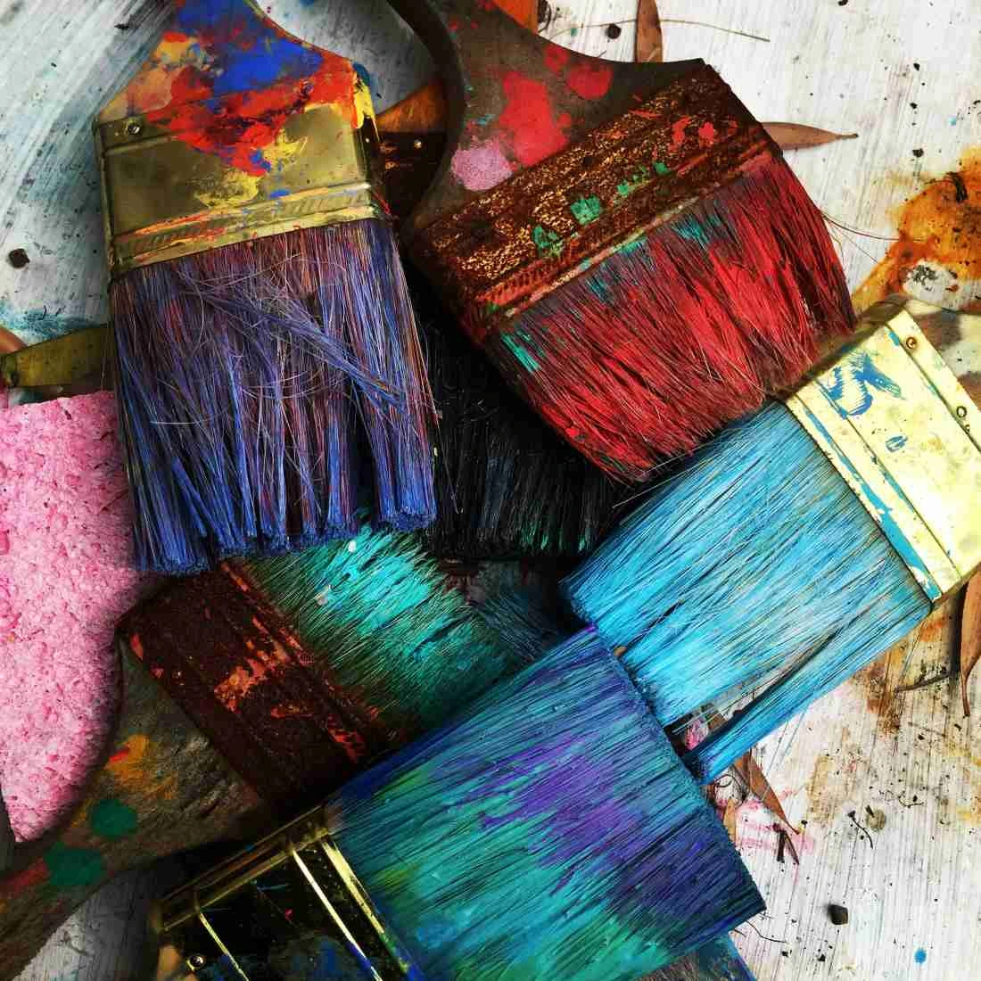 Créativité et design – Un pinceau aux couleurs vives Pinceau de peinture avec des couleurs vives qui se croisent, symbolisant la créativité dans la création de sites web pour indépendants.